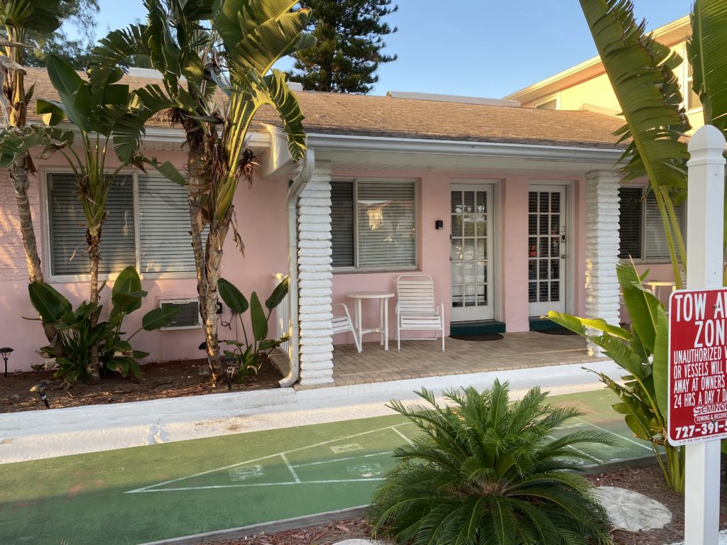a pink house with a tennis court and chairs
