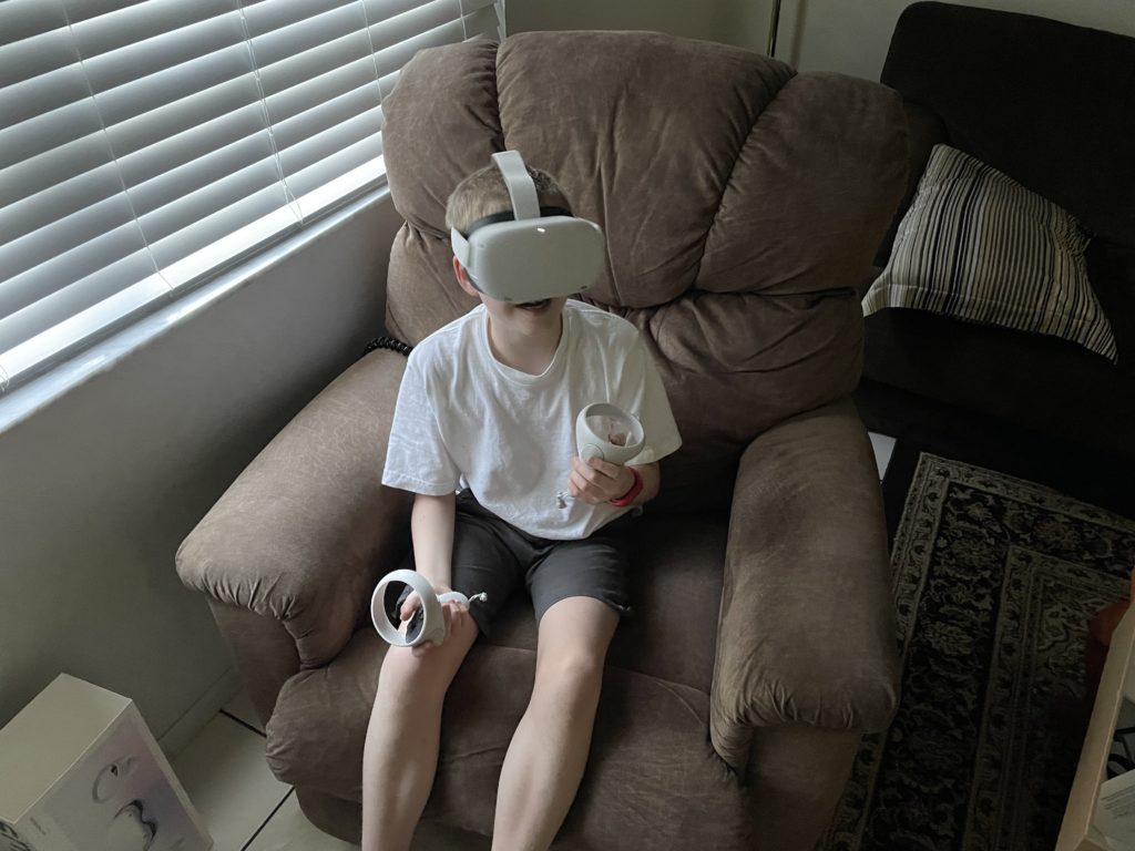 a boy wearing a virtual reality headset sitting in a chair