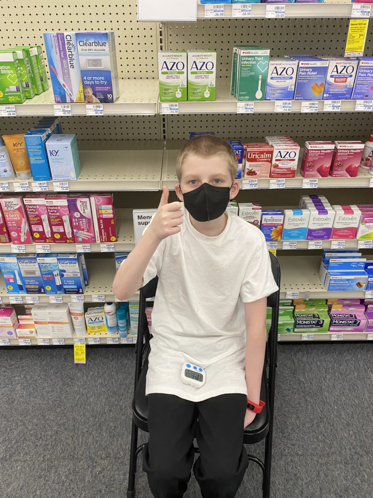 a boy sitting in a chair wearing a face mask