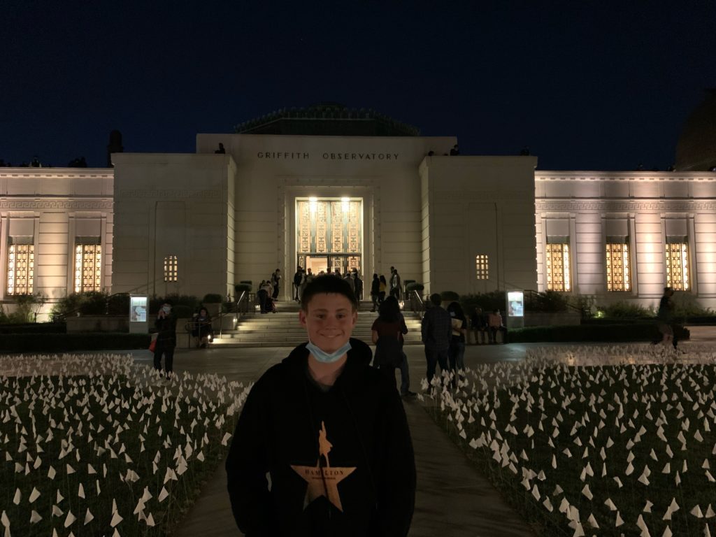 a man standing in front of a building with many white flowers