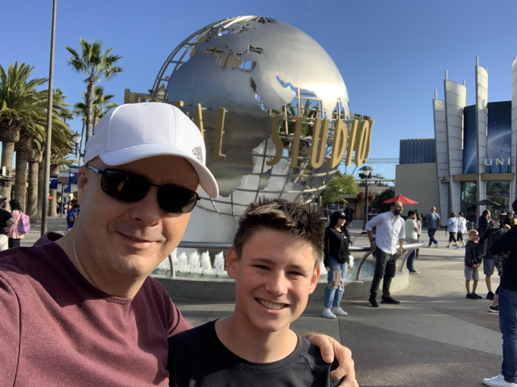 a man and boy taking a selfie in front of a large globe