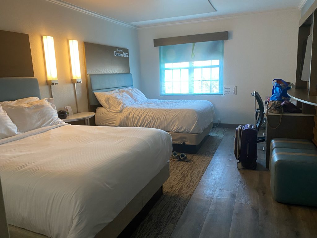 a room with two beds and a suitcase