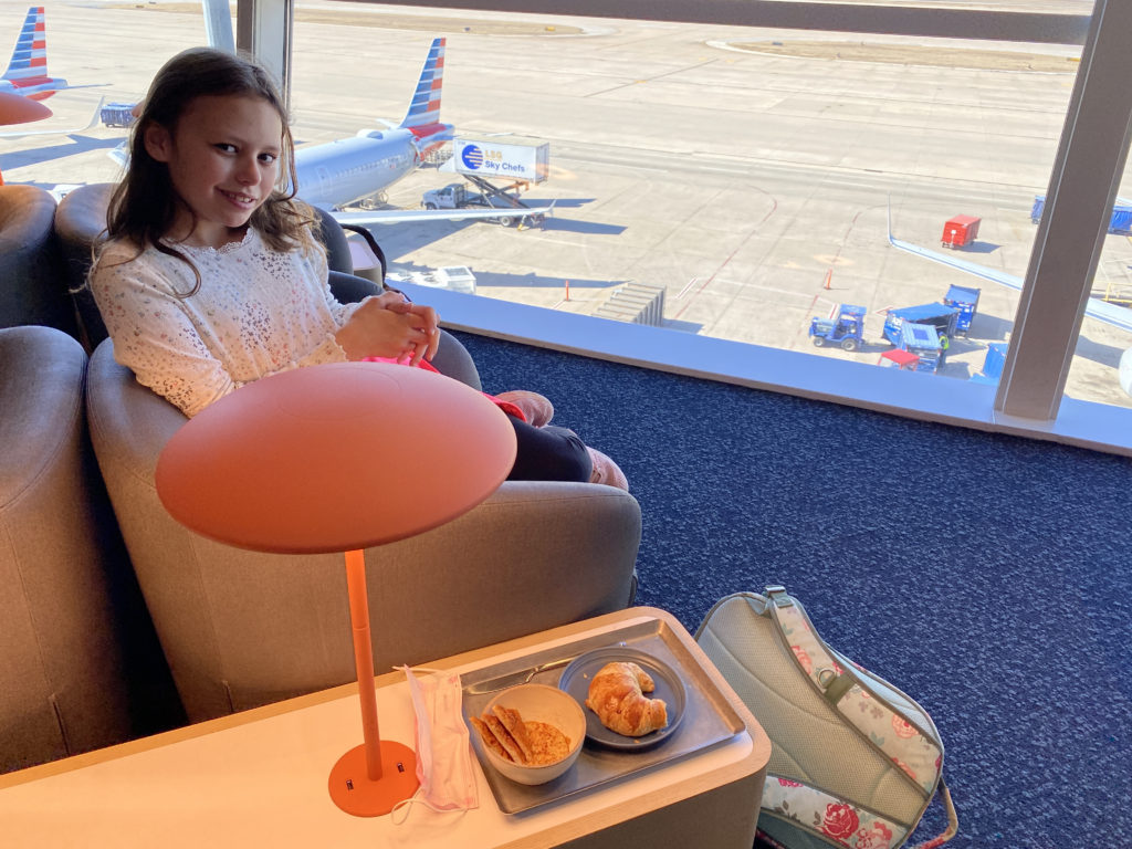 a girl sitting in a chair with food on a table