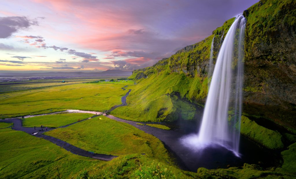 a waterfall over a green valley