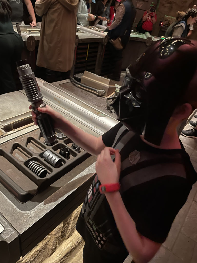 a child wearing a mask and holding a light saber