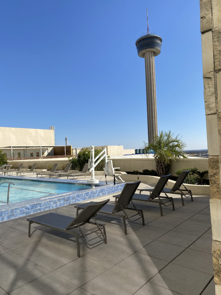 a pool with lounge chairs and a tower in the background