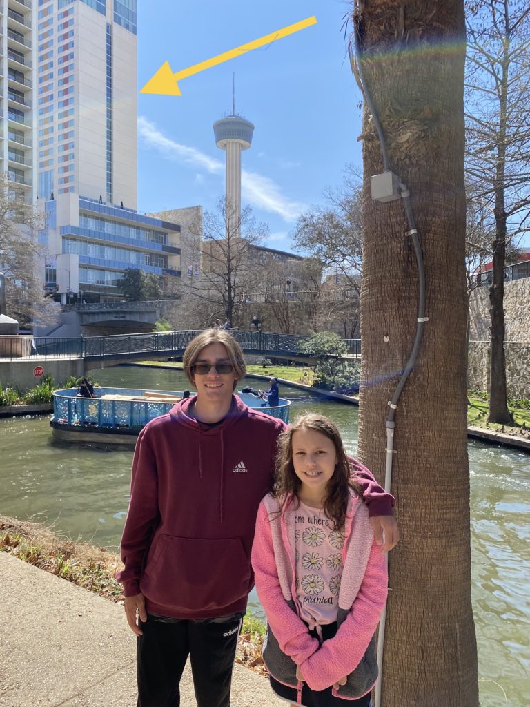 a man and girl standing next to a tree