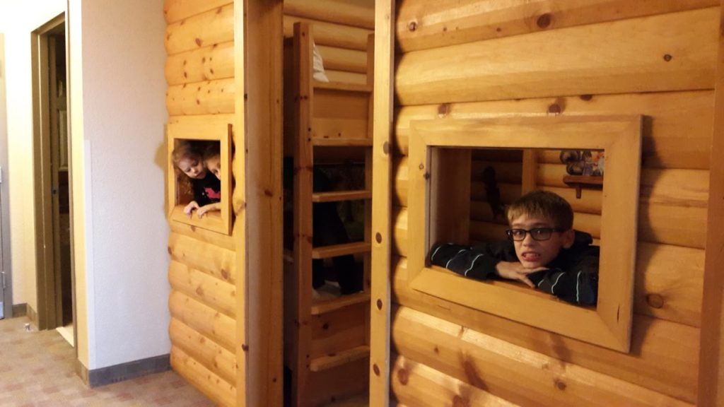 a group of kids looking out of a wooden cabin