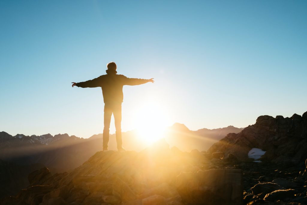 a person standing on a mountain with their arms outstretched