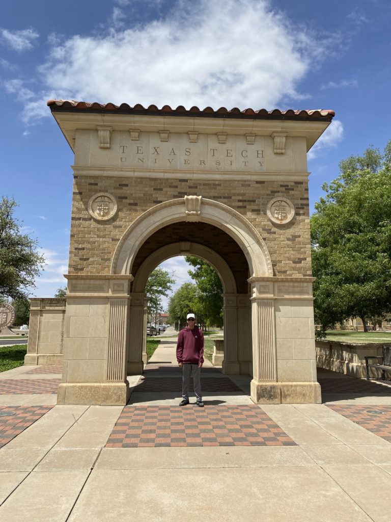 a man standing in front of a stone archway