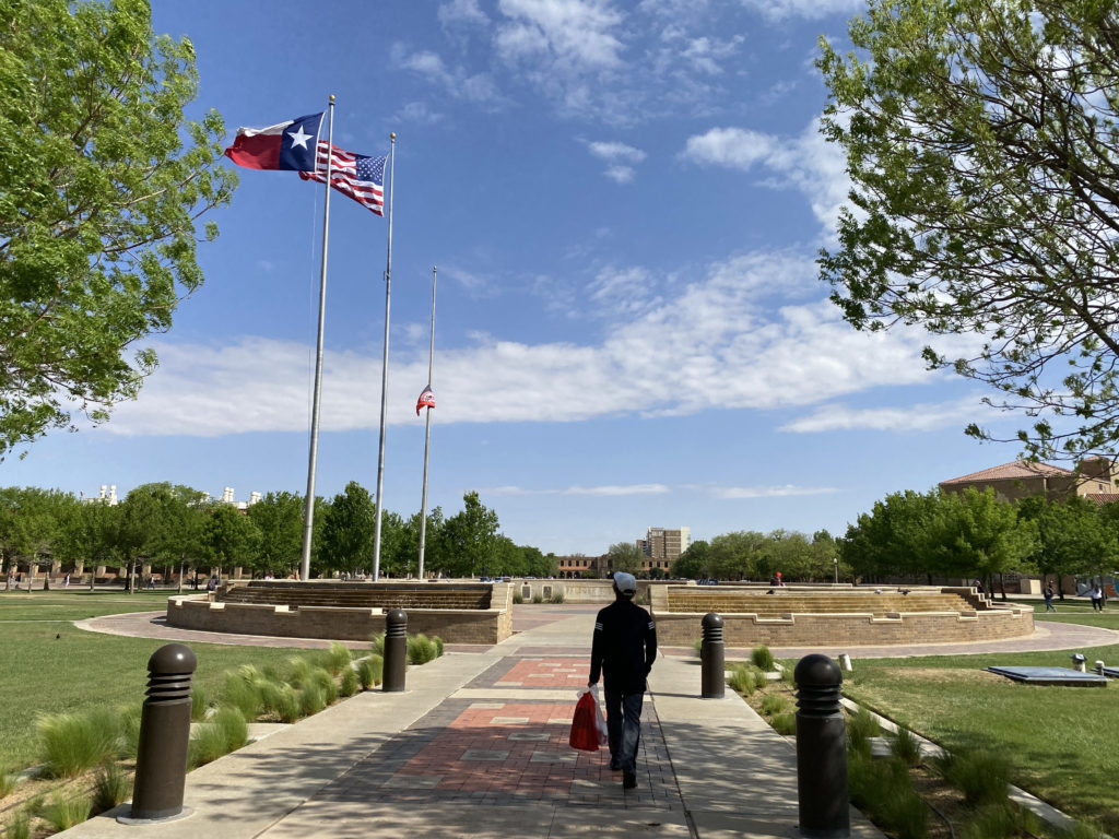 a man walking on a sidewalk with flags on poles