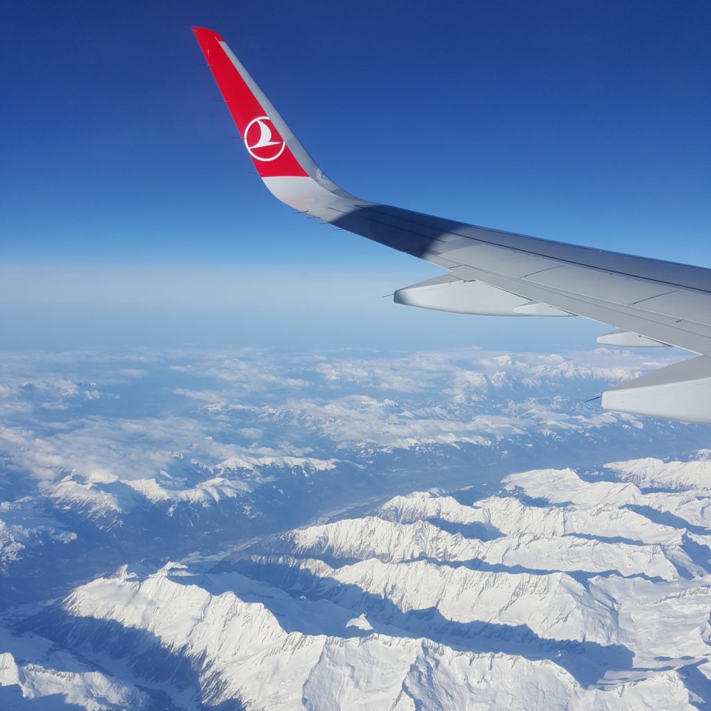 an airplane wing with snow covered mountains in the background