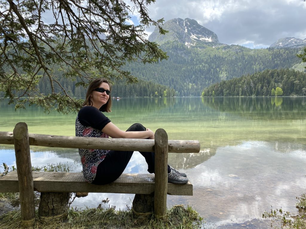 a woman sitting on a bench by a lake