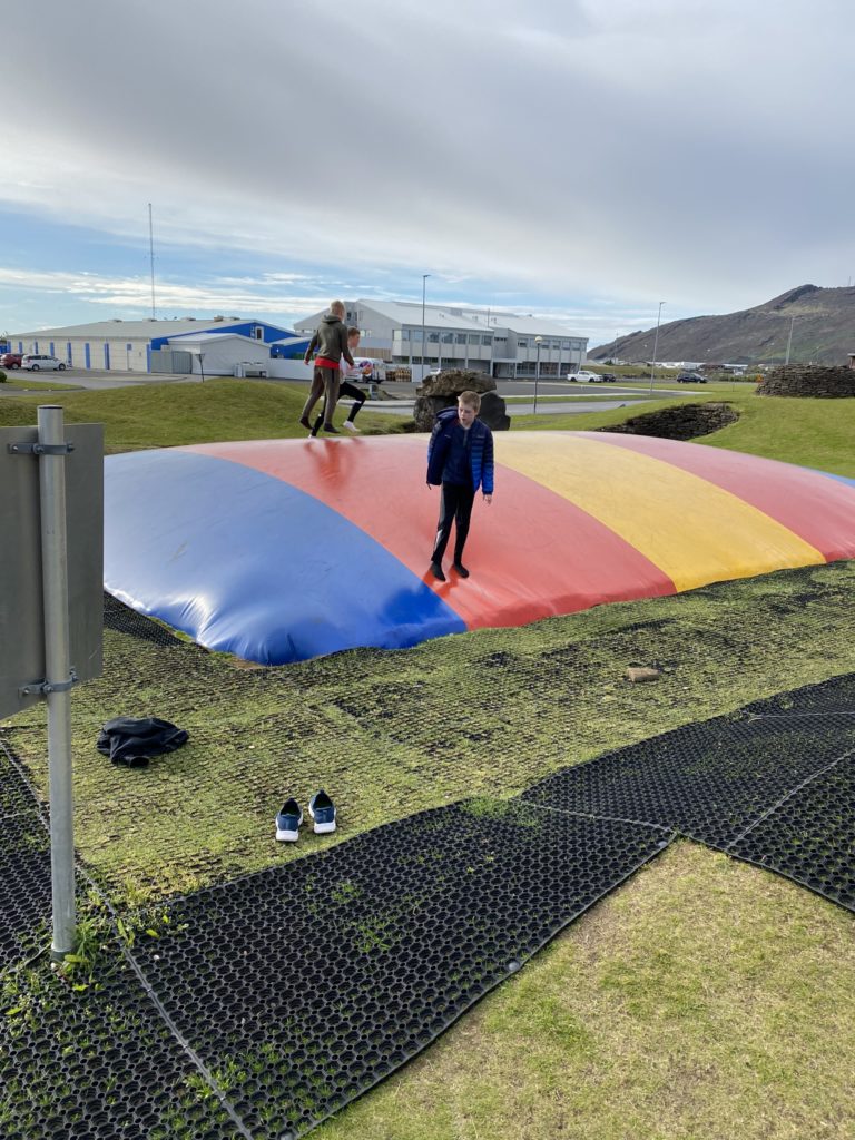 a group of kids jumping on a large colorful trampoline