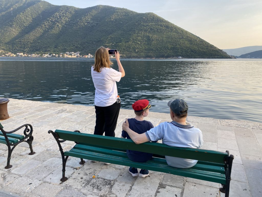 a woman taking a picture of a group of people sitting on a bench