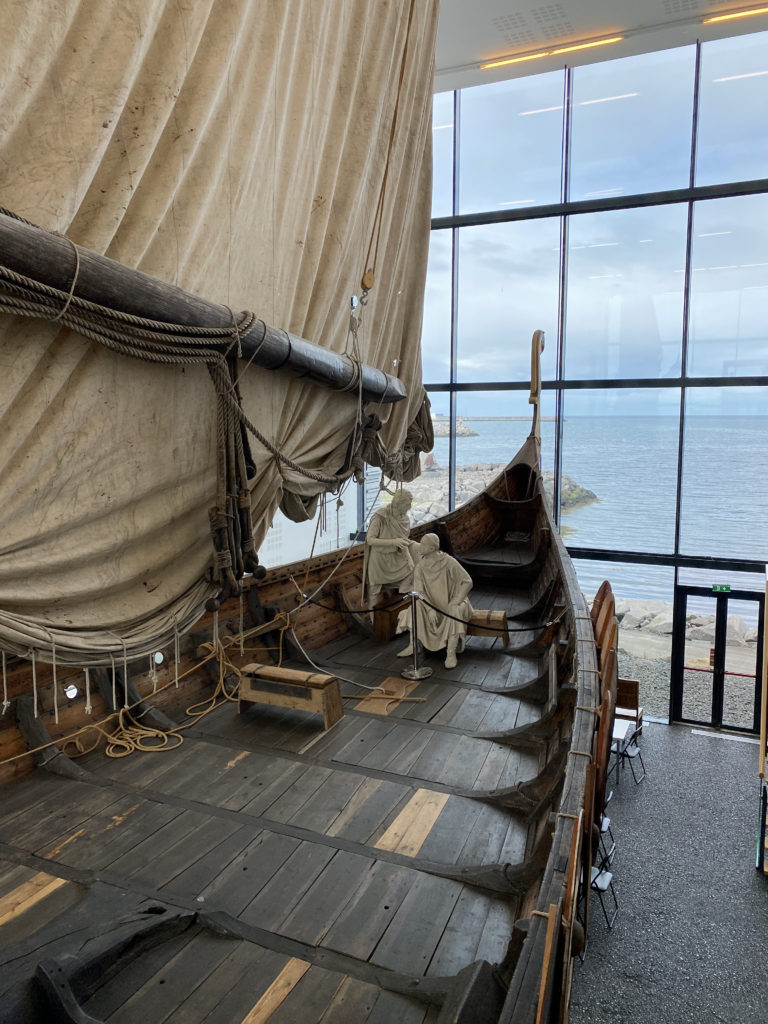 a wooden boat with a large curtain and a body of water