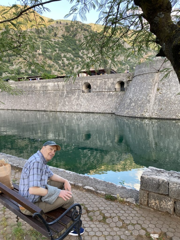 a man sitting on a bench by a body of water