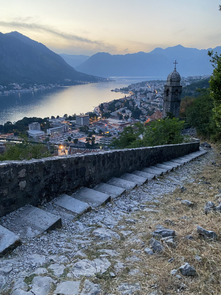 a stone stairs leading up to a city by a river