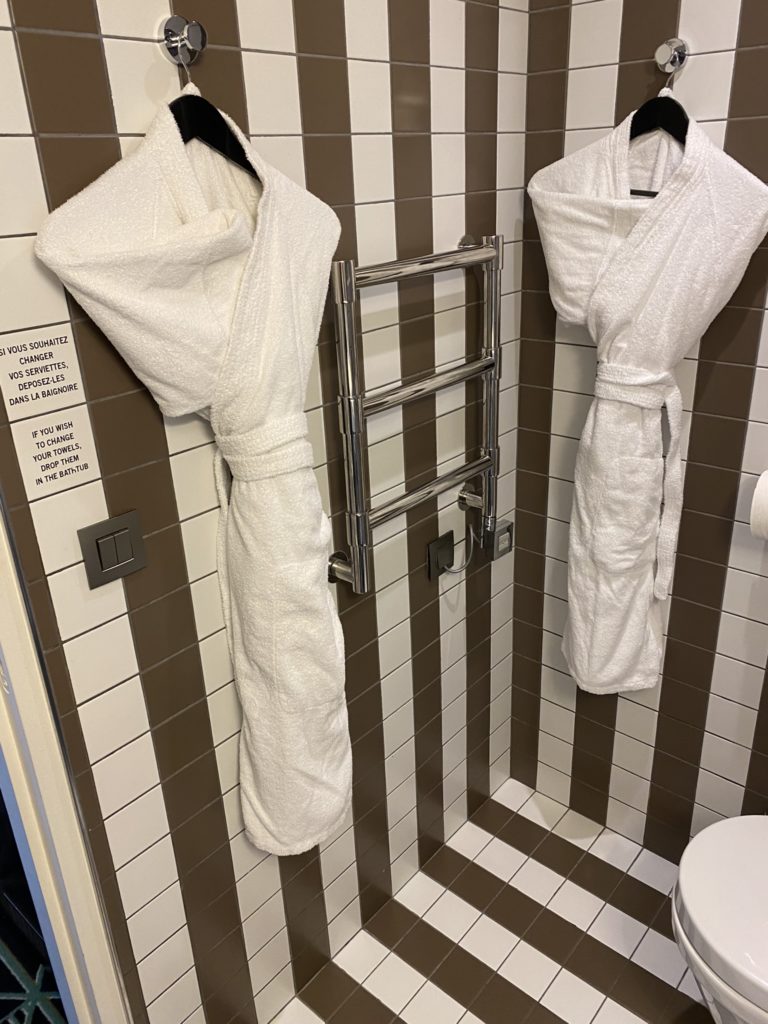 a bathroom with white bathrobes and towels