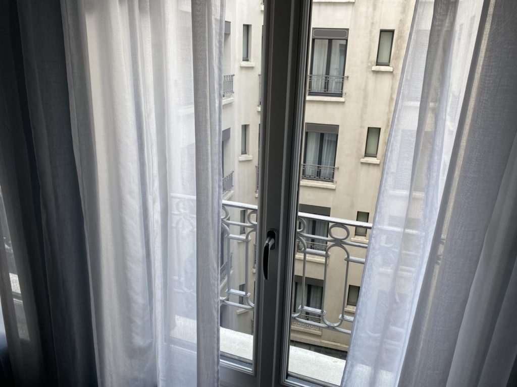 a window with white curtains and a balcony