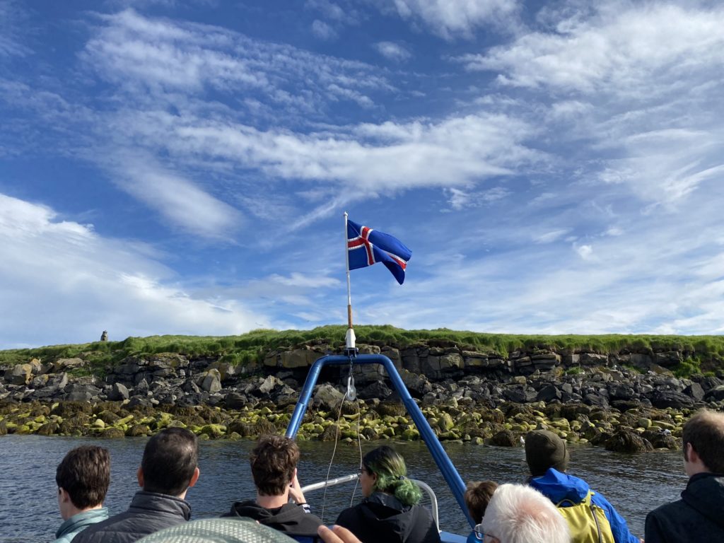 a group of people on a boat with a flag on the top