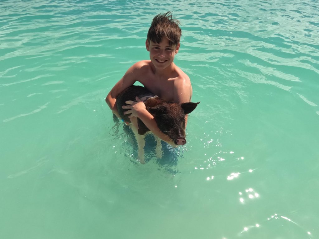 a boy holding a pig in water
