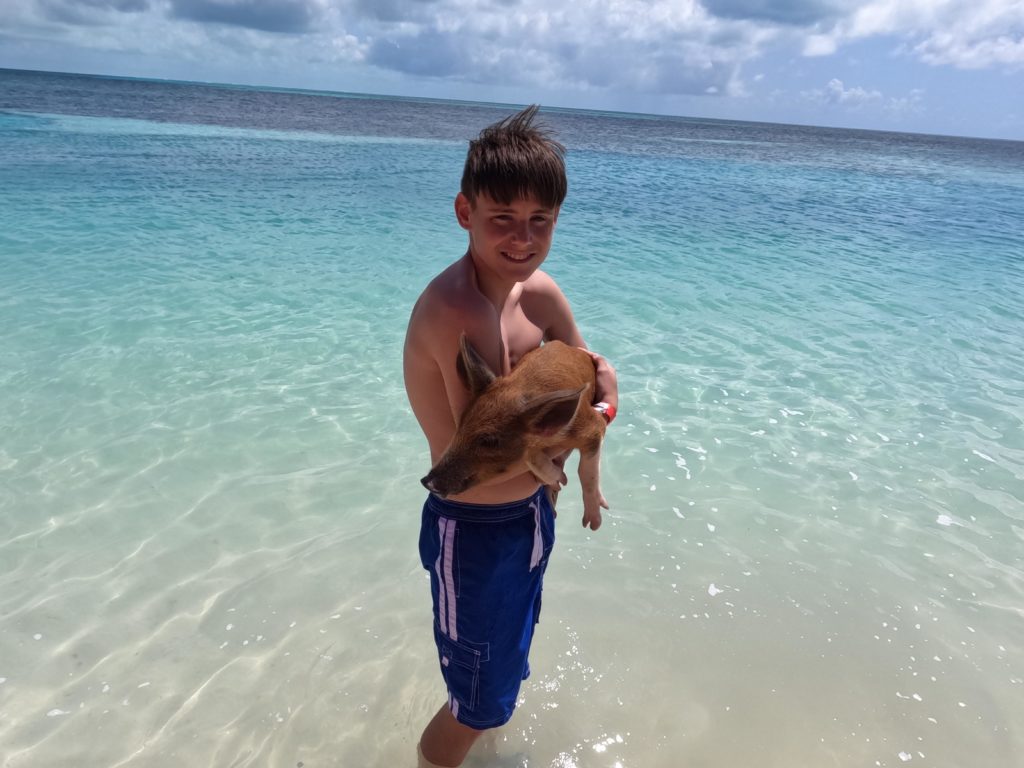 a boy holding a pig in the water