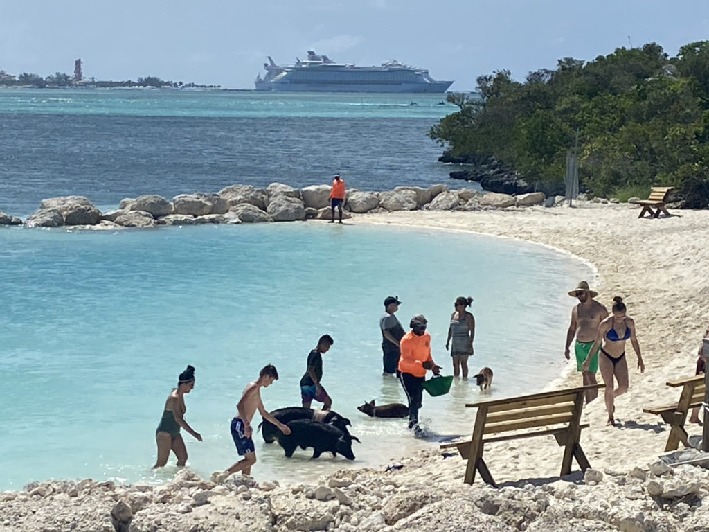 a group of people in a body of water with a boat in the background