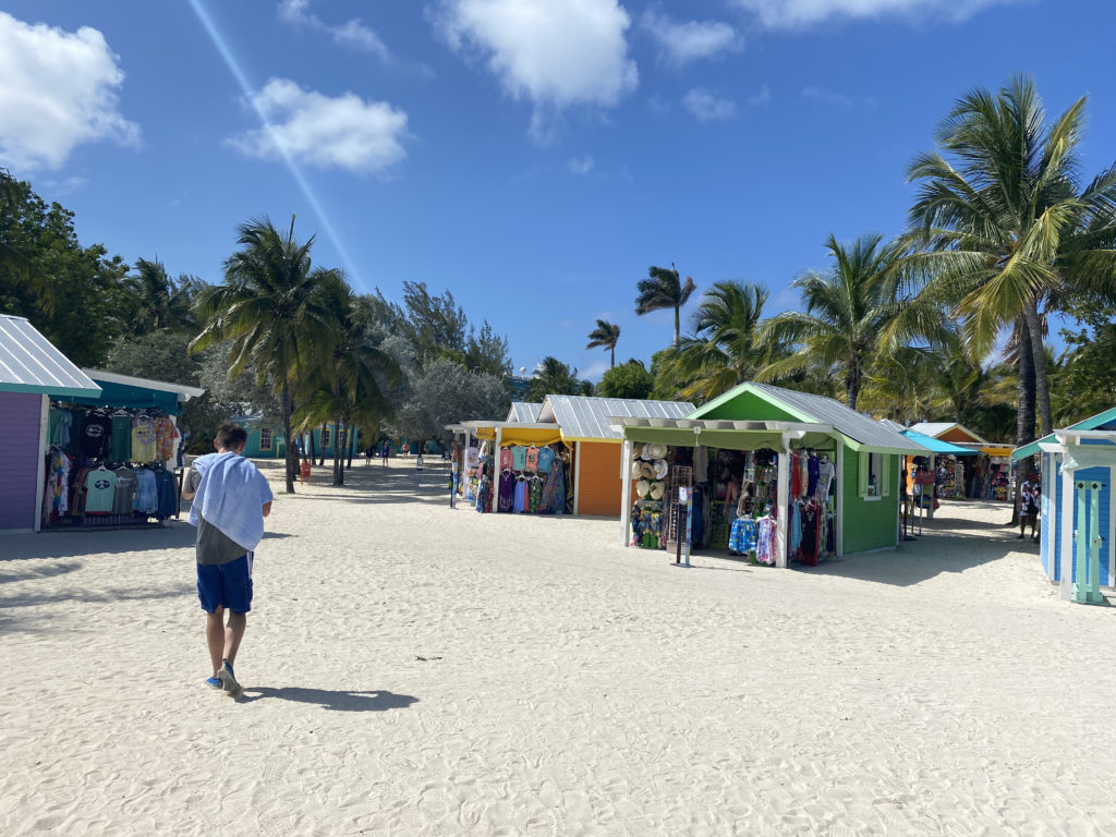 a man walking on a beach with many small shops