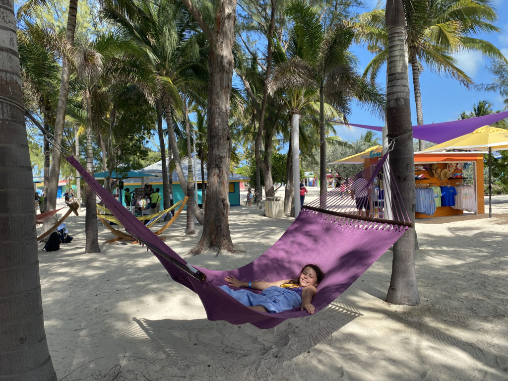 a girl lying in a hammock on a beach