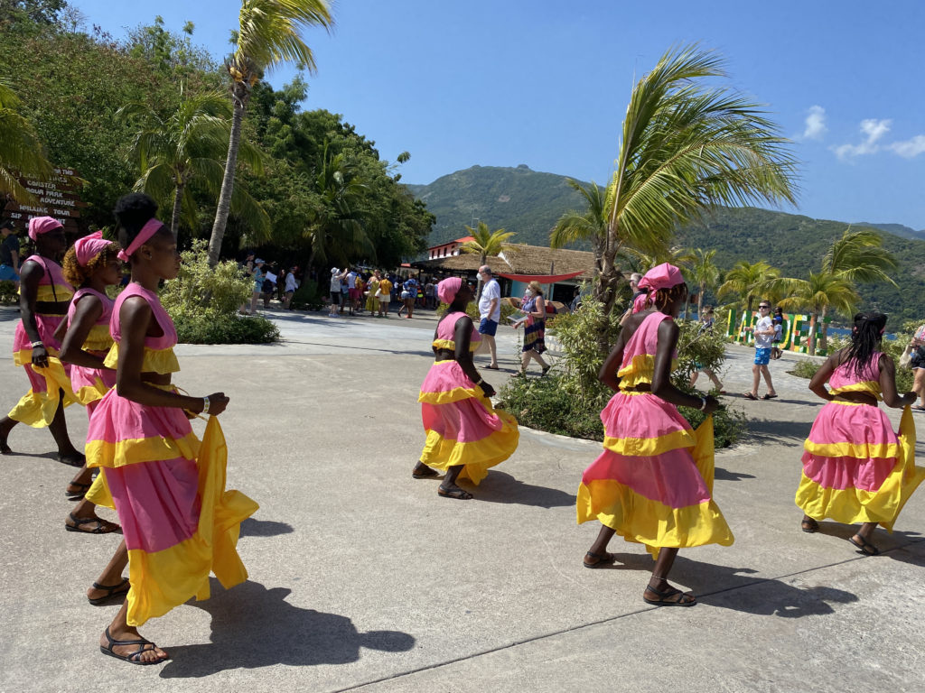 a group of women in pink and yellow dresses walking on a sidewalk