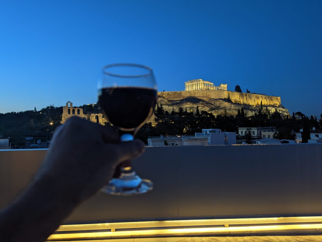 a hand holding a glass of wine with a building in the background