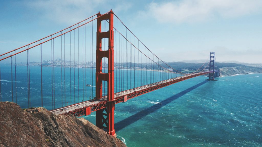 a red bridge over water with Golden Gate Bridge in the background