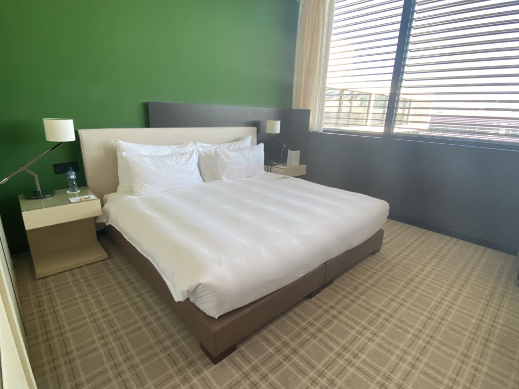 a bed with white sheets and a green wall