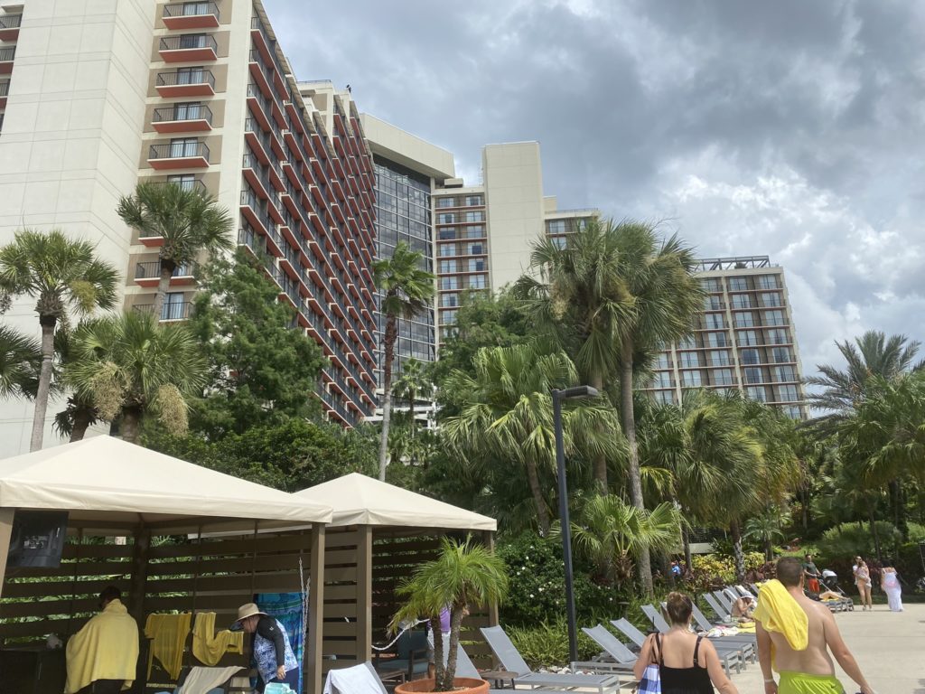 a group of people in a pool with palm trees and buildings