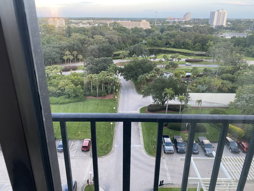 a view of a parking lot and trees from a balcony
