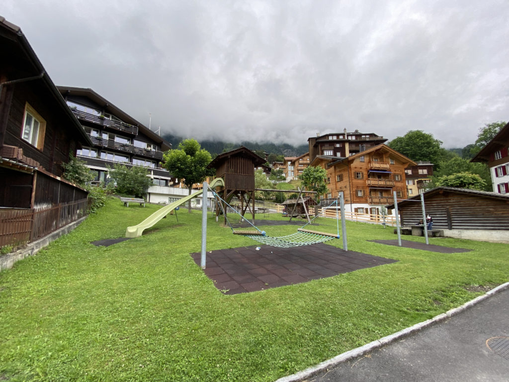 a playground in a park with buildings in the background
