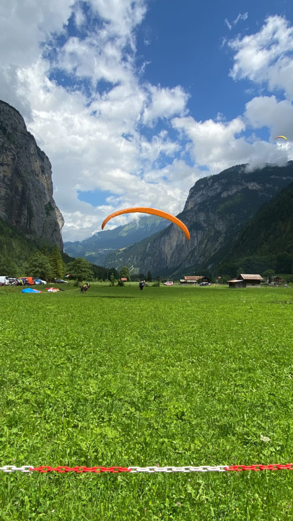 a green field with a large orange parachute in the air