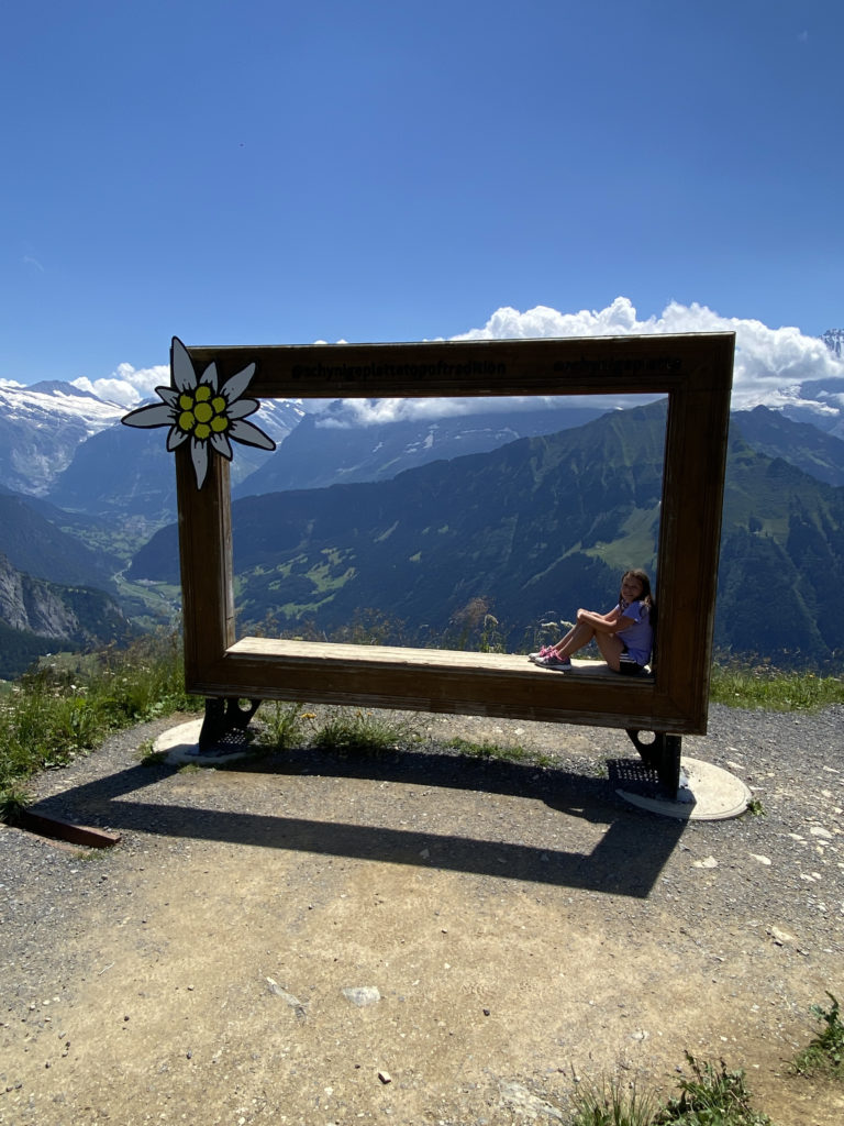a girl sitting in a frame with mountains in the background