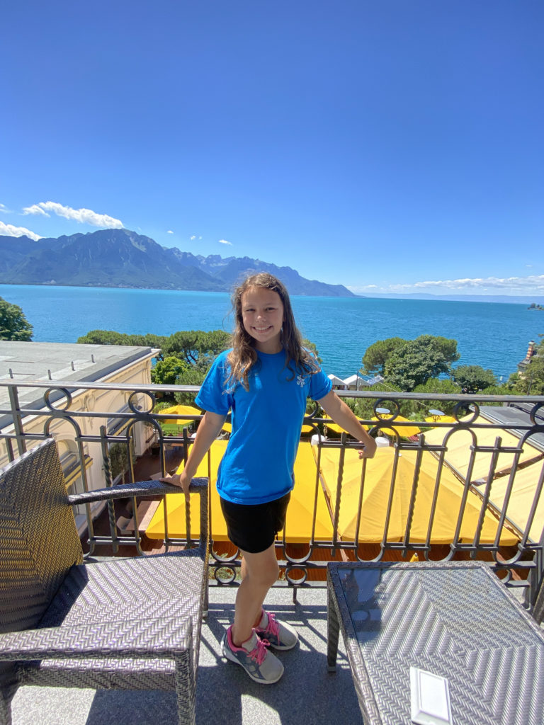 a girl standing on a balcony overlooking a body of water