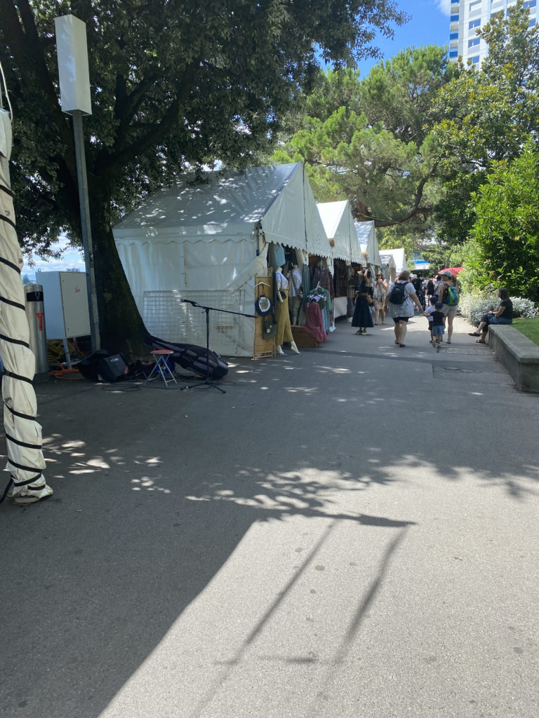 a group of people walking down a sidewalk with tents