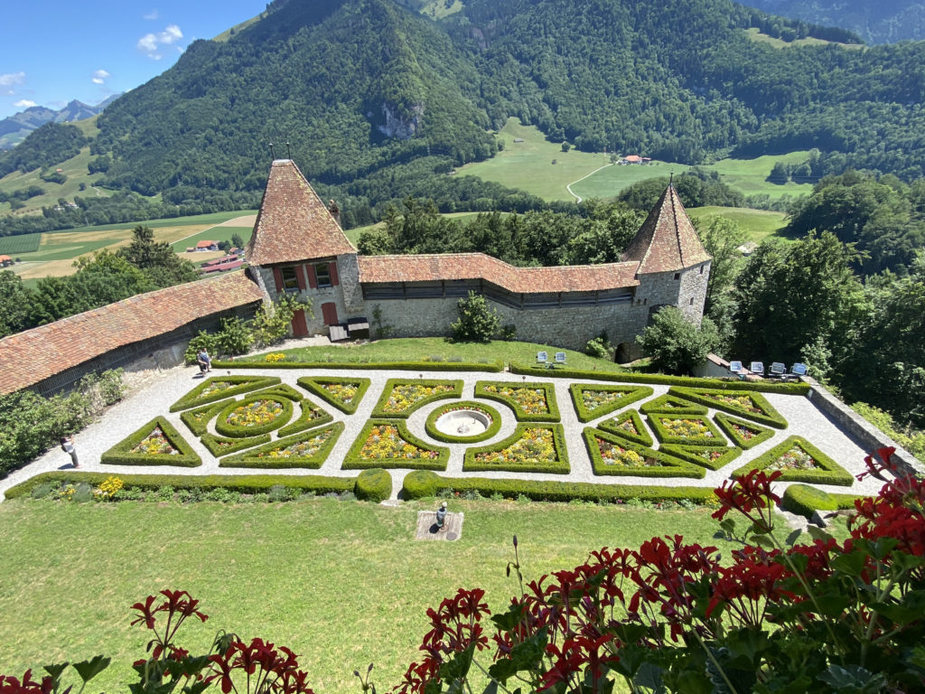 a garden with a stone building and a large mountain in the background