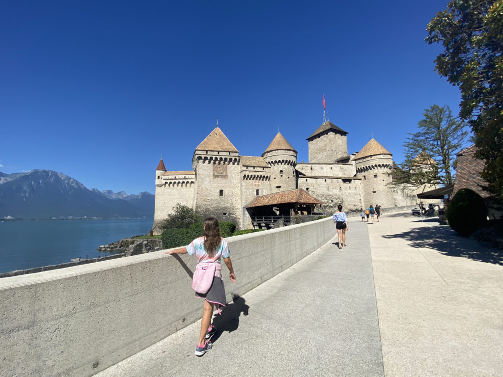 a group of people walking on a sidewalk by a castle