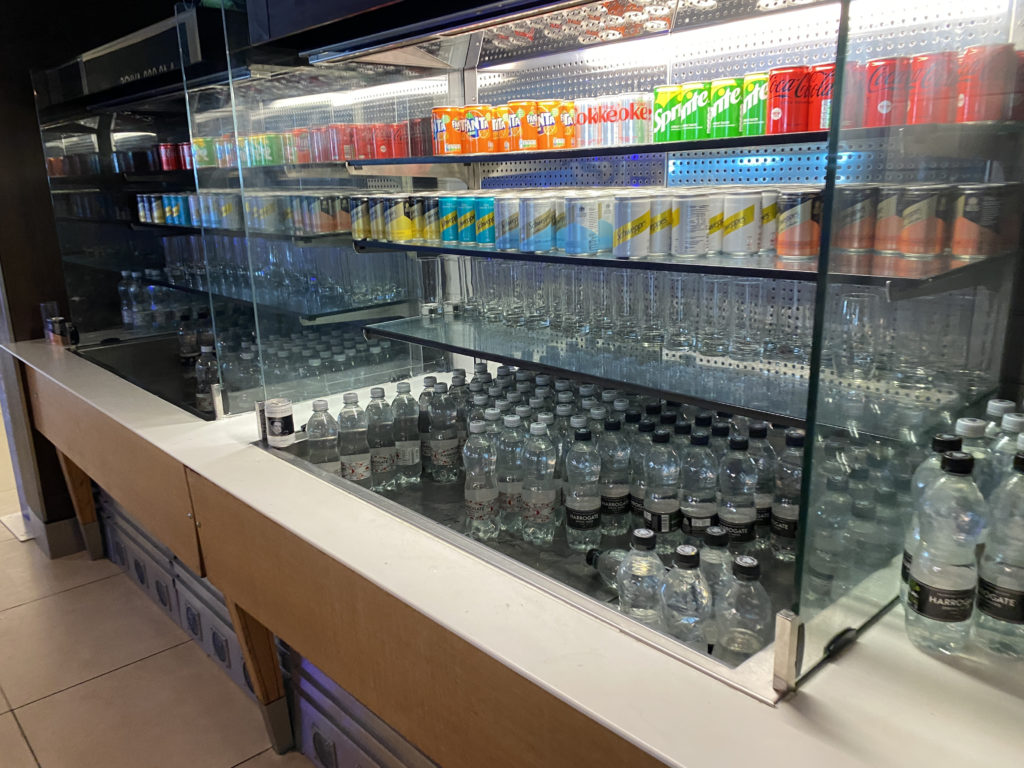 a display case with bottles of soda and cans