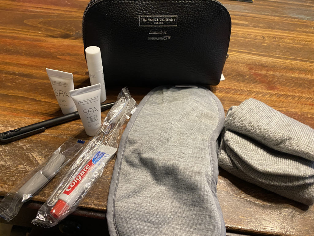 a black bag with a black pouch and a black eye mask on a wood surface
