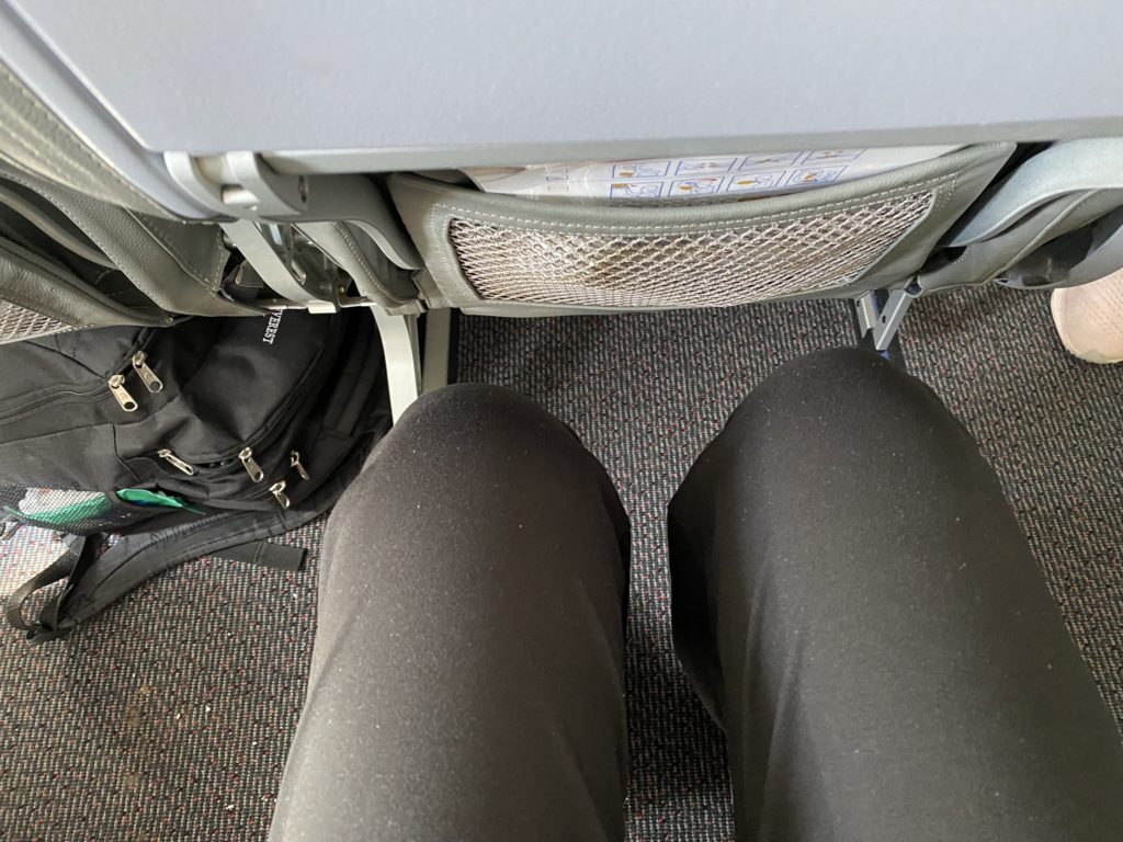 a person's legs and a backpack on the floor