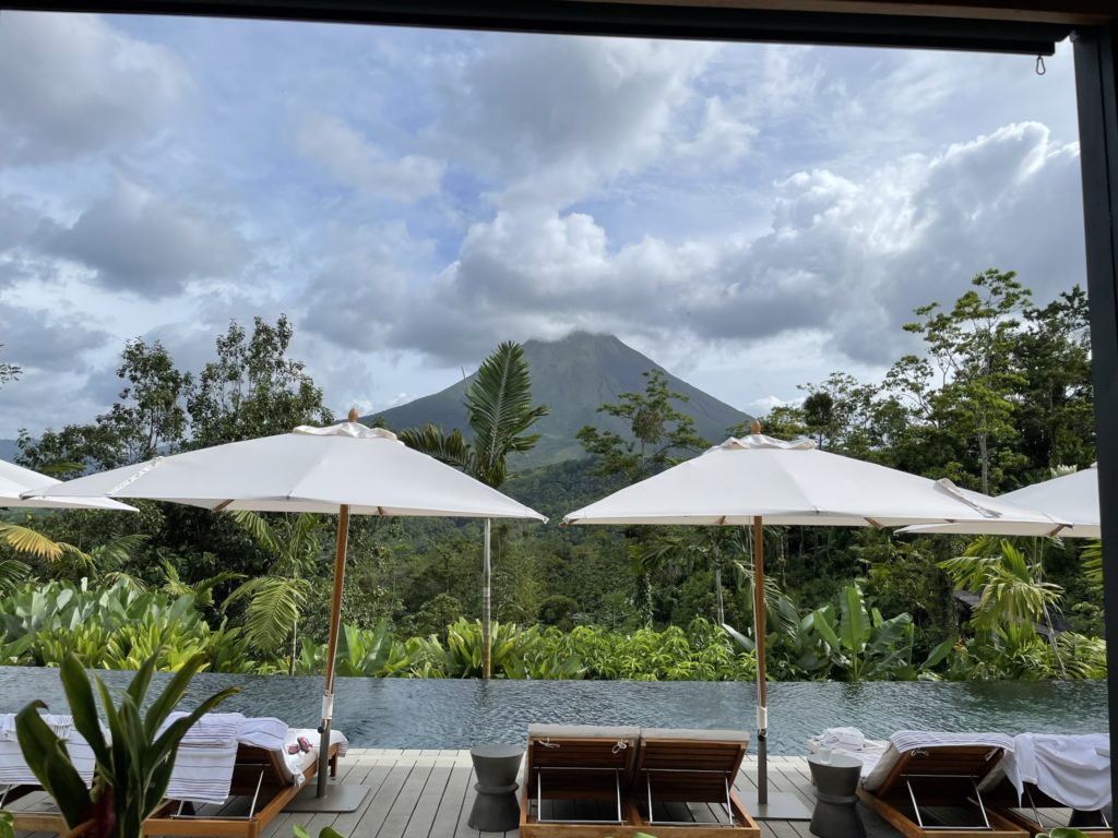 a pool with umbrellas and chairs in front of a mountain