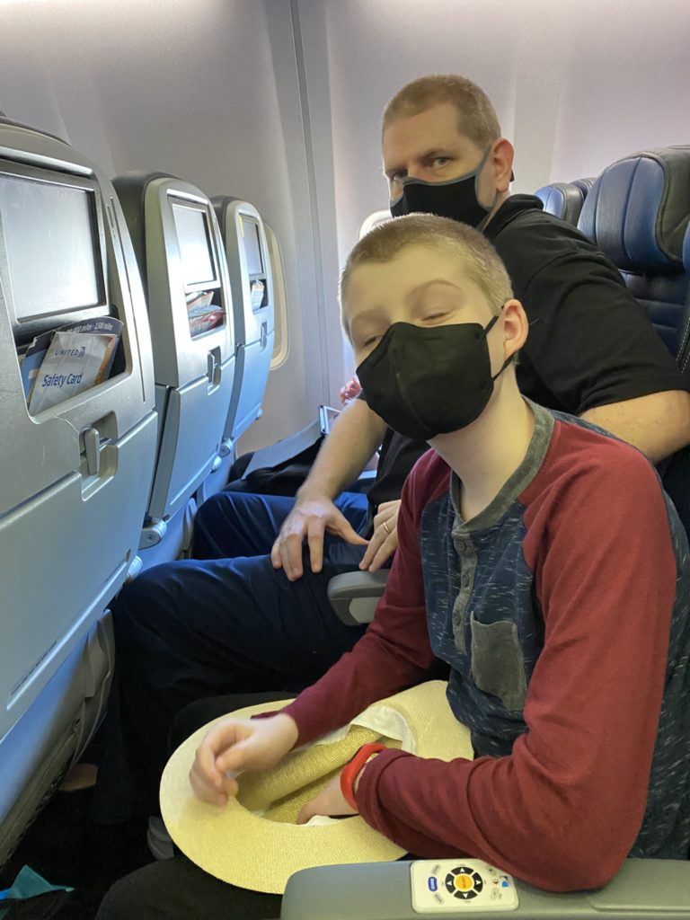 a man and boy wearing face masks on an airplane