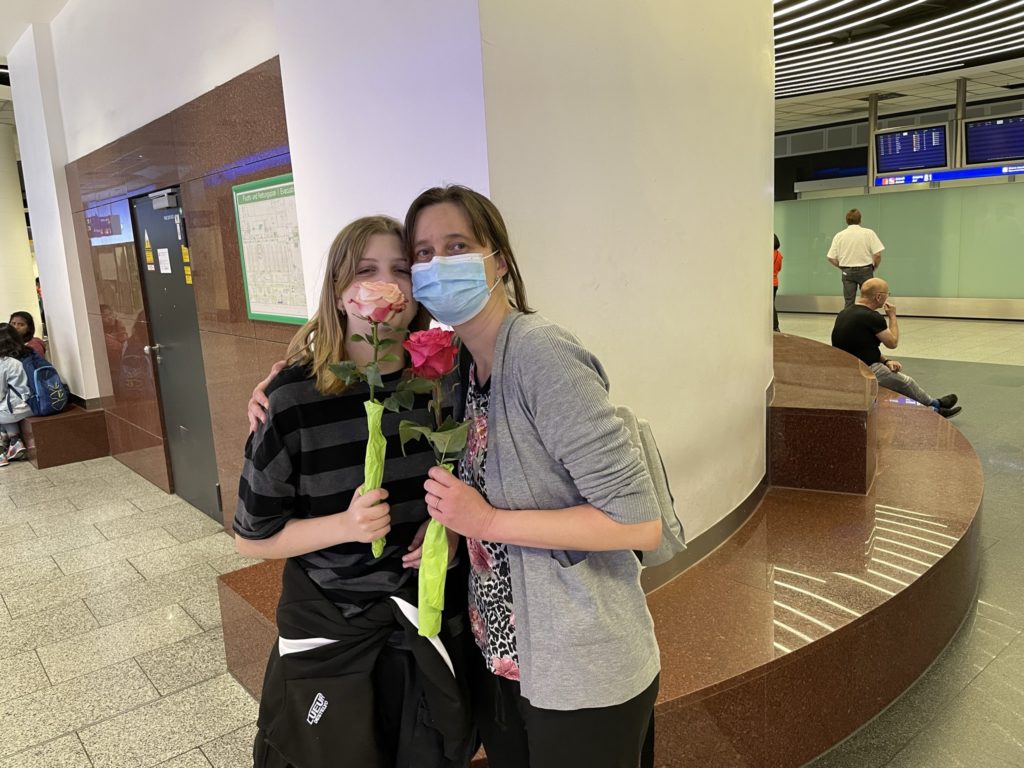 a woman and a girl wearing face masks and holding flowers