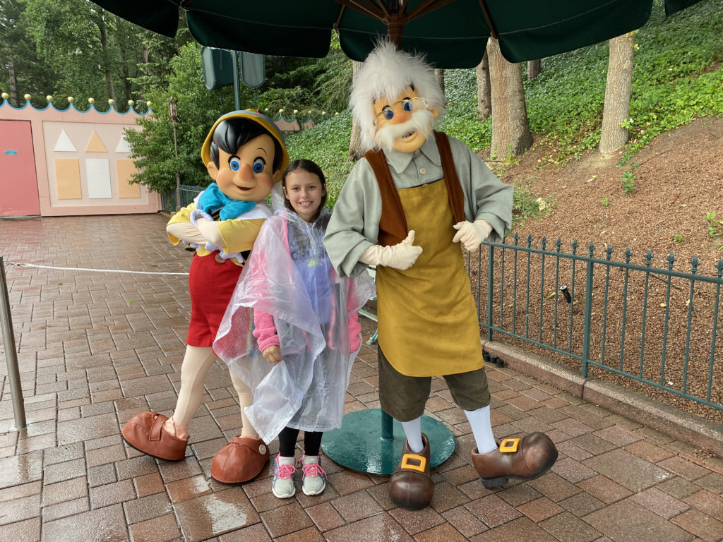 a girl standing under an umbrella with a group of people in clothing